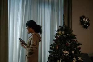 A person feeling overwhelmed and stressed during the holiday season, surrounded by festive decorations and family members.