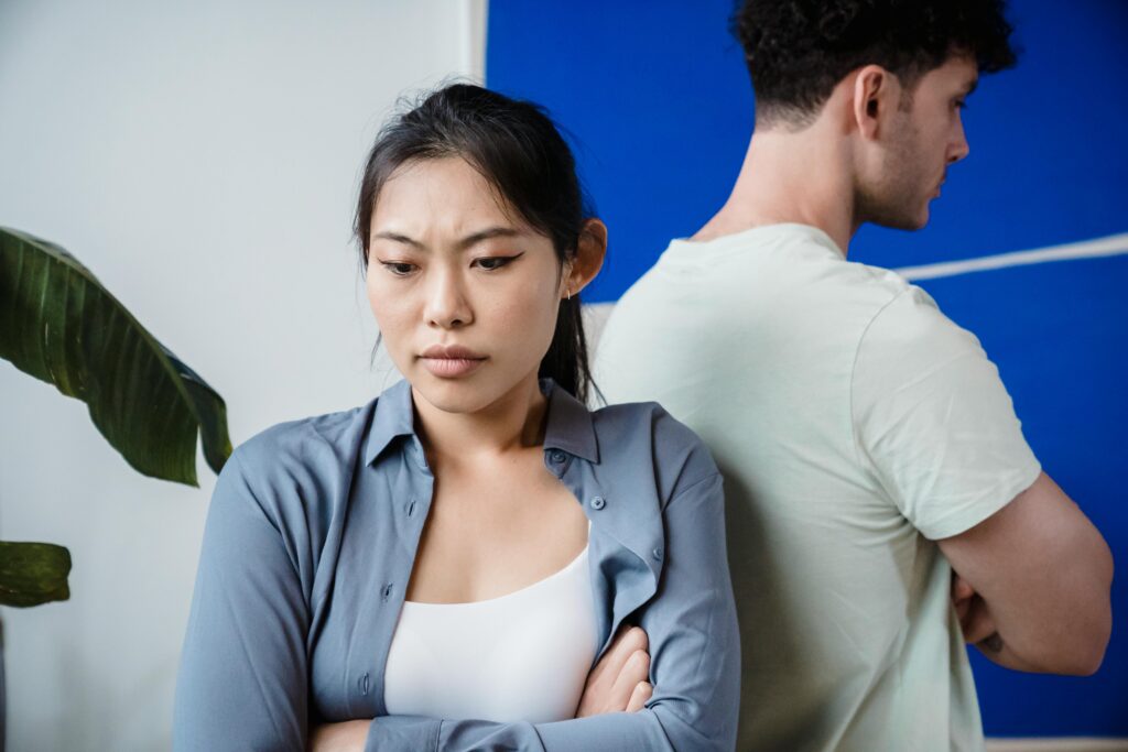 A woman and man sitting back-to-back after an argument, showing emotional distance and relationship tension.