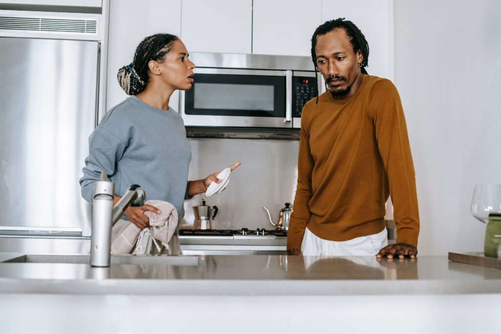 Couple having a tense conversation in their kitchen, representing relationship anxiety, overthinking, and reassurance-seeking in romantic relationships.